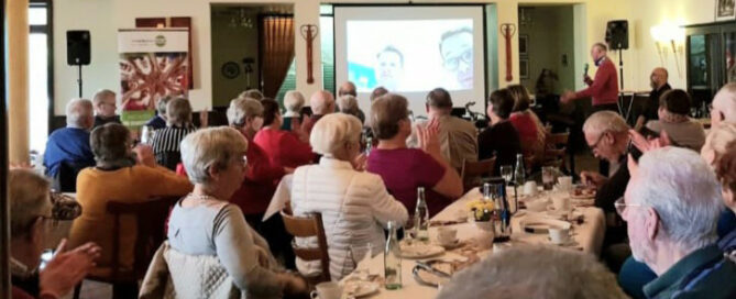 Publikum im Saal vor einer Leinwand